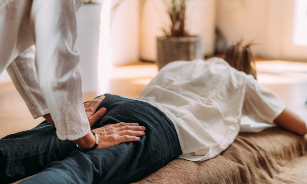 Physical therapist helping patient perform sciatica stretching exercises in Houston clinic